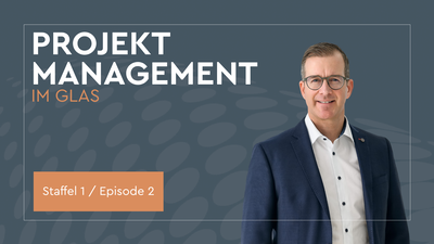 Auf der rechten Seite zeigt das Bild den Podcast Host Christian Dürk. Er trägt eine Brille, ein weißes Hemd und einen dunkelblauen Anzug. Links im Bild ist der Schriftzug „Projektmanagement im Glas“ in Versalien zu sehen. Darunter befindet sich ein orangener Kasten, in dem „Staffel 1 / Episode 2“ steht. Der Hintergrund ist in einem dunklen Blaugrau gehalten mit einer stilisierten Welle aus helleren blaugrauen Punkten.